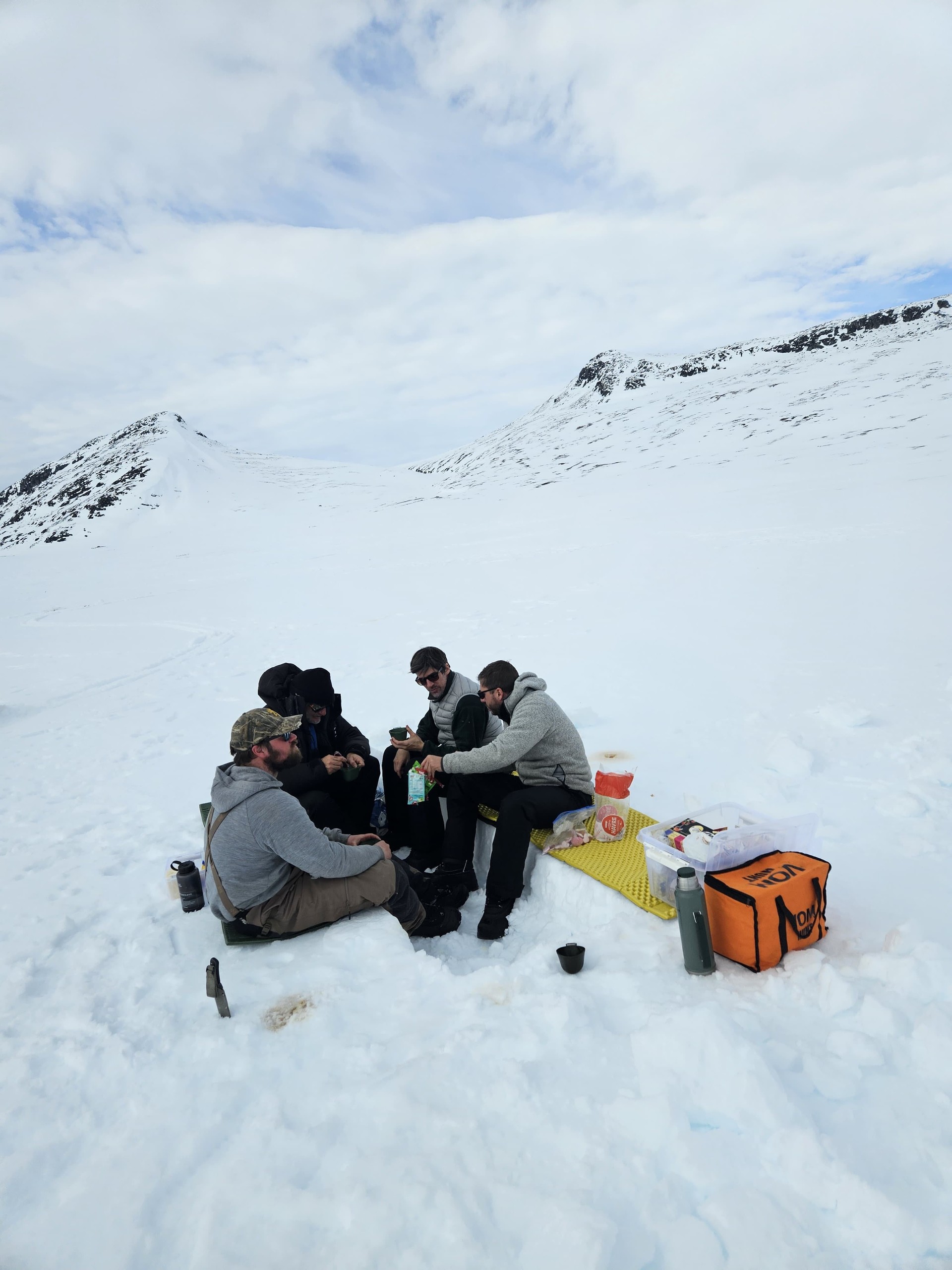 People having a picnic on snow in a mountainous area.