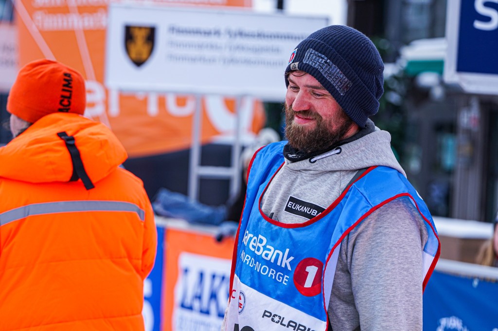 Man in sportswear smiling at outdoor winter event.