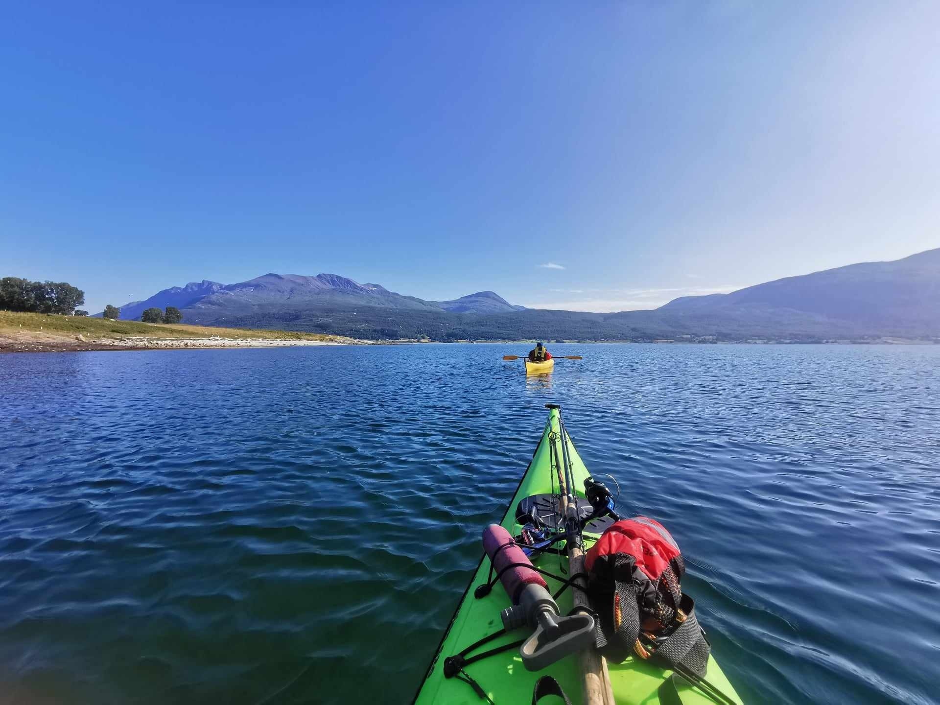 Kayak on a lake with mountains in the background under a clear blue sky.
