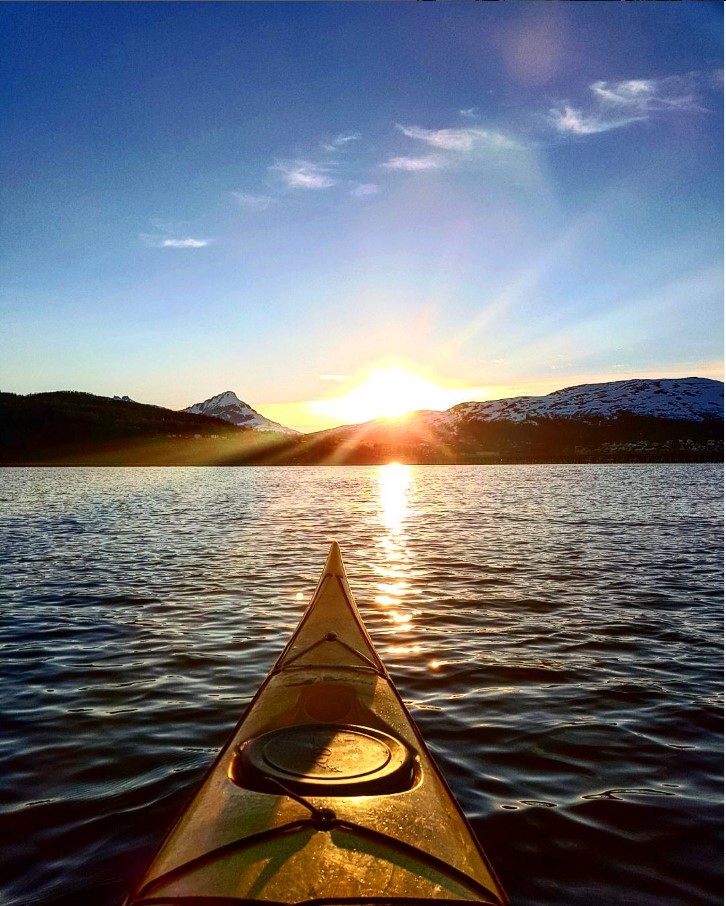 Kayak on water at sunset with mountains and clear sky in background